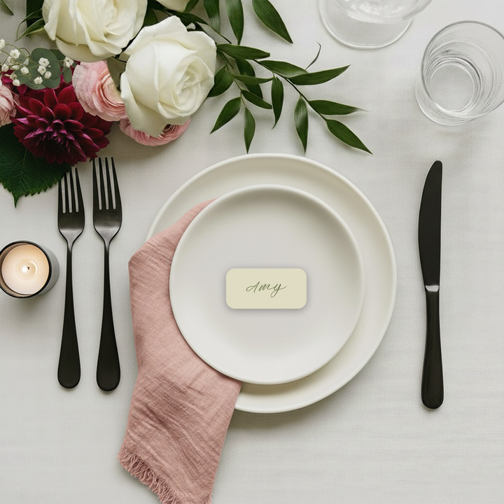 Personalised wedding place card with guest name on a white table setting.