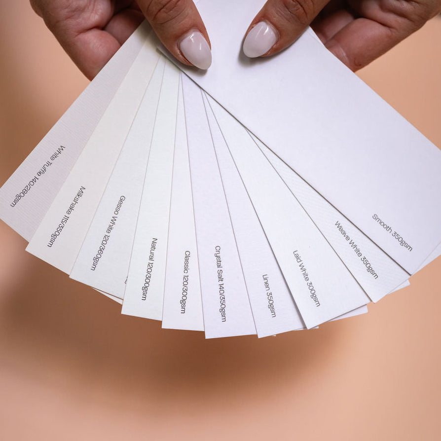 Hands holding a stack of white wedding stationery card-stock samples