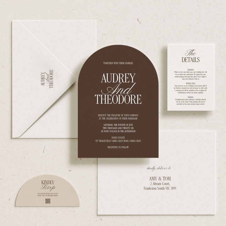 A coordinated wedding invitation suite laid out on a light textured background, including a dark brown arch-shaped main card, white envelope, white details card, white invitation card, and a small cream RSVP card.