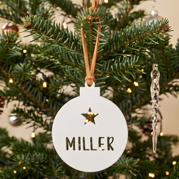 A personalized white Christmas ornament with a gold star and the name &