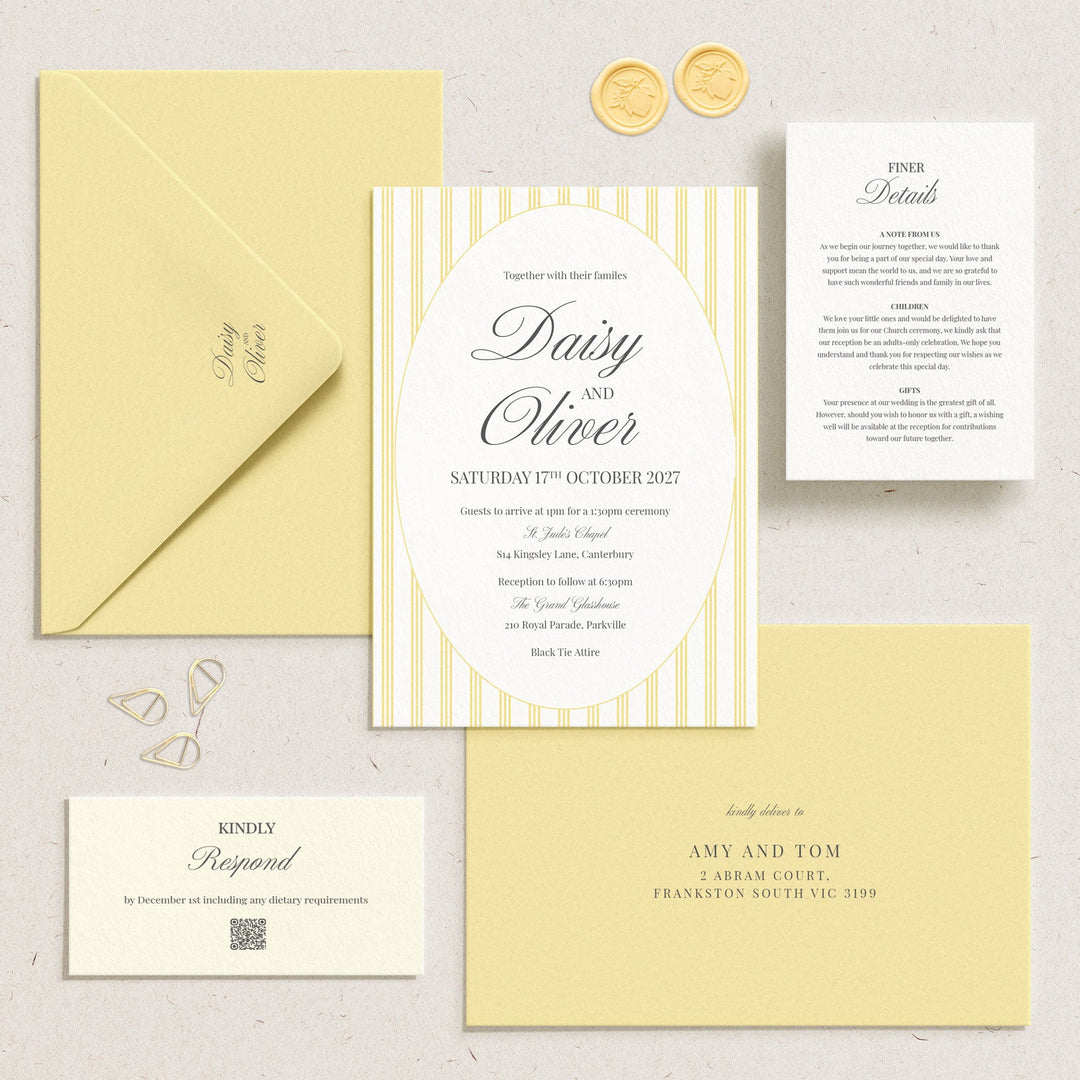 A styled flat-lay of a wedding invitation suite on a light textured background, featuring a central striped oval invitation card, a pale yellow envelope, a white details card, a cream reply card, and a pale yellow reception card, with two gold wax seals.