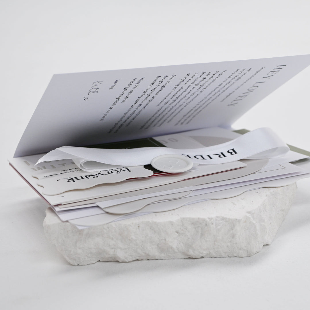 Ivory &amp; Ink wedding stationery sample pack folder opened to show invitation, place card and ribbon samples inside