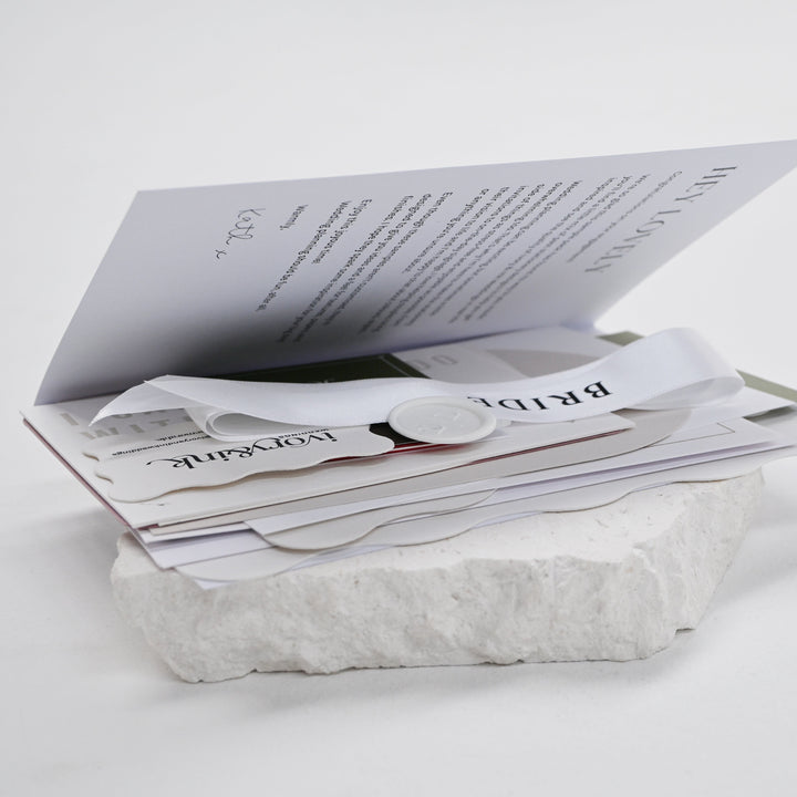 Ivory &amp; Ink wedding stationery sample pack folder opened to show invitation, place card and ribbon samples inside