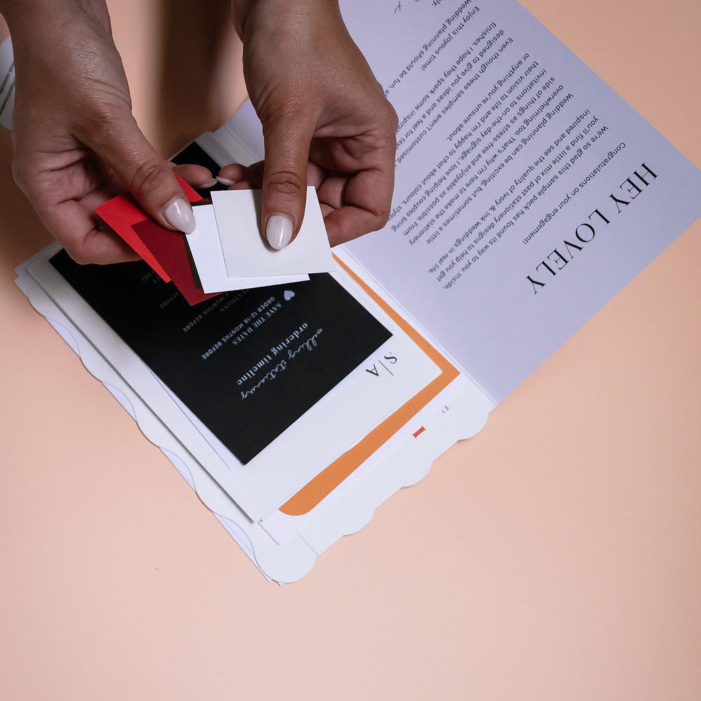 Person using a red tool to open a white box with a black label on a beige surface.