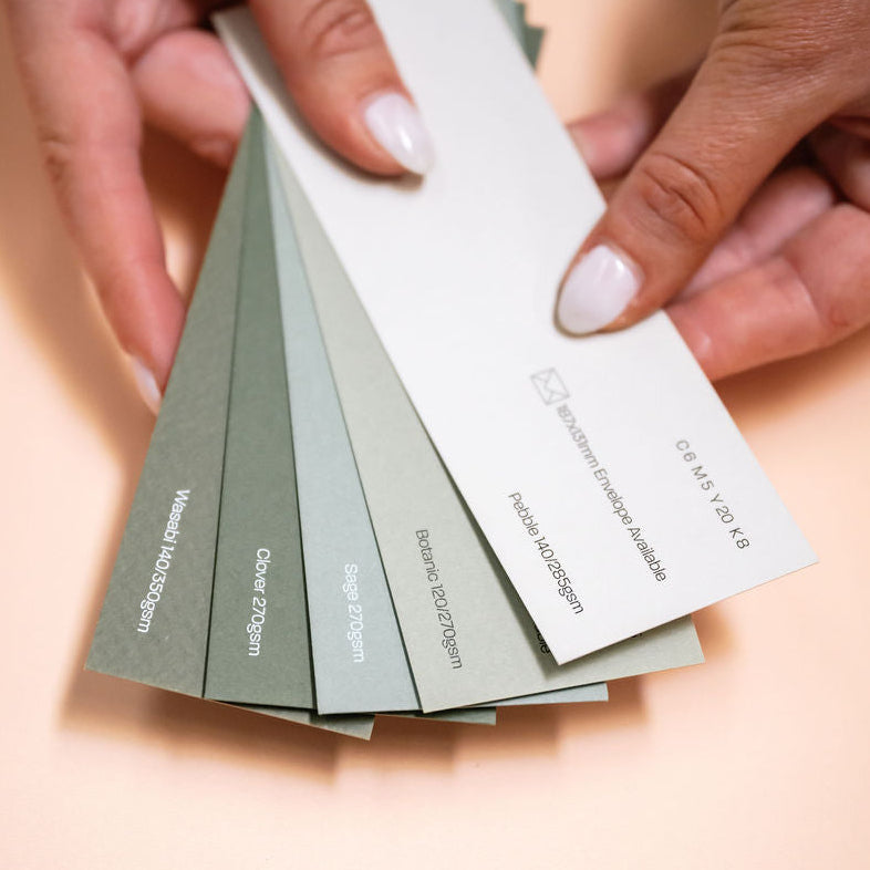 Hands holding a set of color swatch cards on a light background