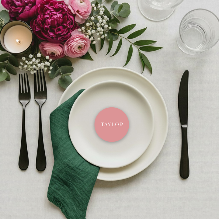 Pink wedding place card in a circle shape with white text